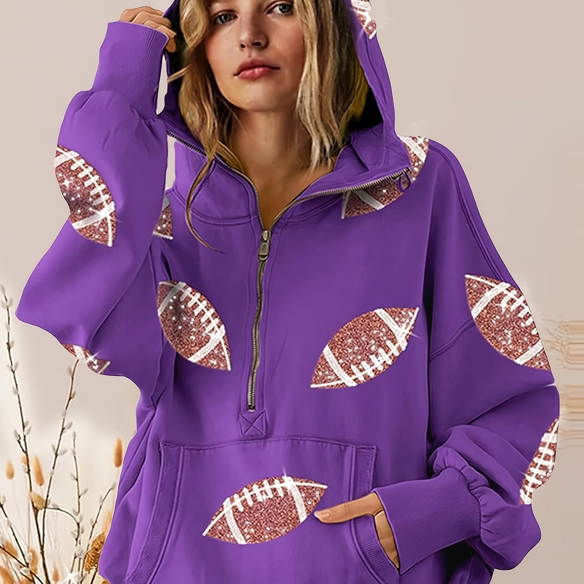Purple hoodie with football designs on sleeves and front pocket worn by a person.