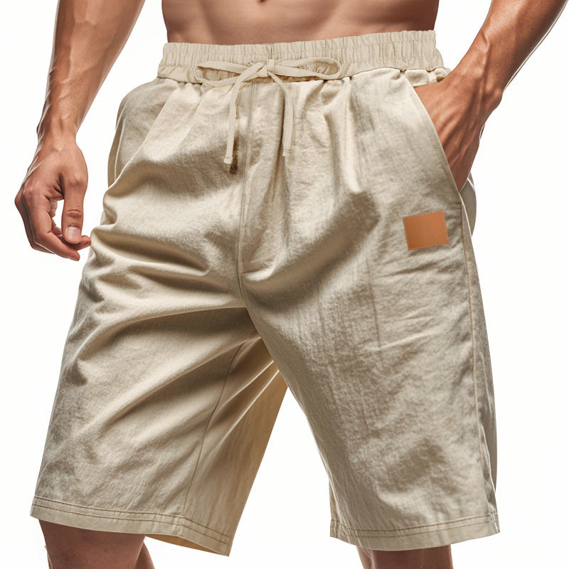 Beige shorts with a drawstring and patch pocket on a white background
