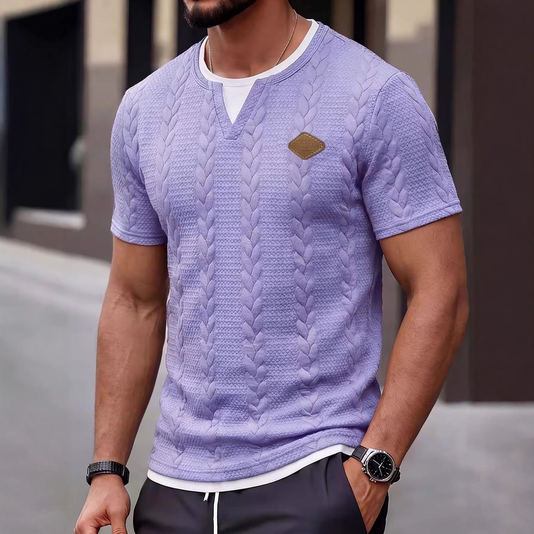 Man wearing a textured purple t-shirt with a logo on a blurred background