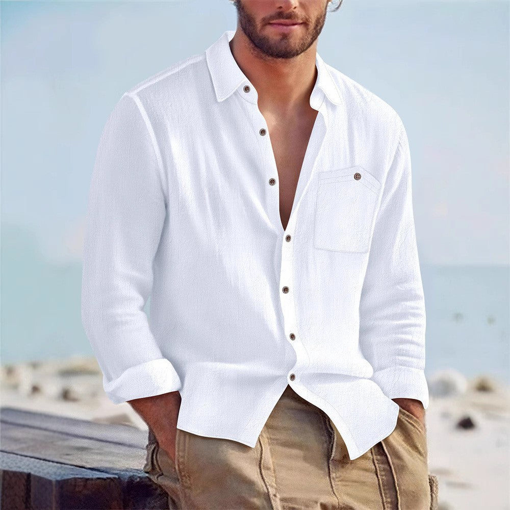 Man wearing a white button-up shirt and beige pants with a blurred beach background
