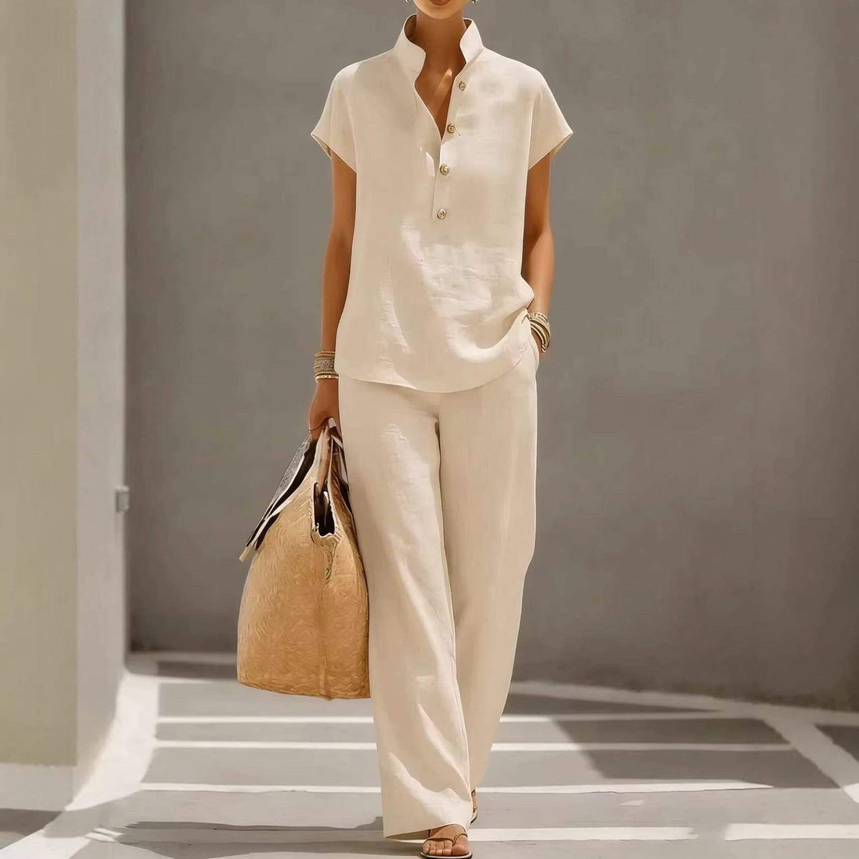 Person wearing a beige outfit holding a bag in a minimalistic setting