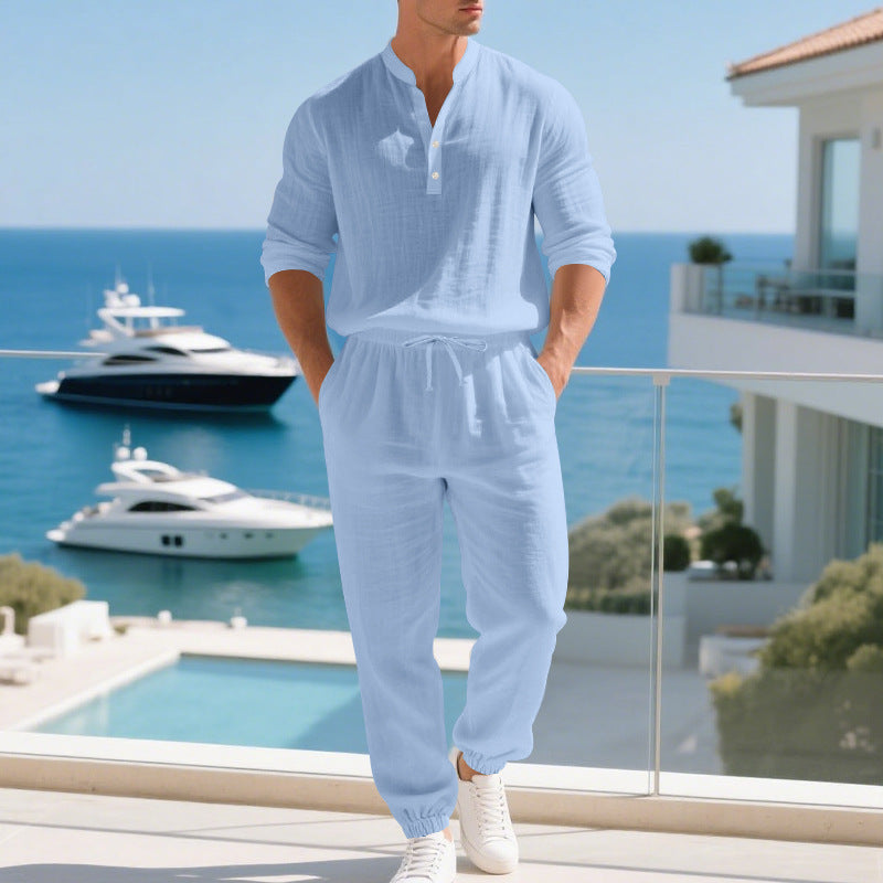 Man in light blue outfit standing on a balcony with ocean view and yachts.