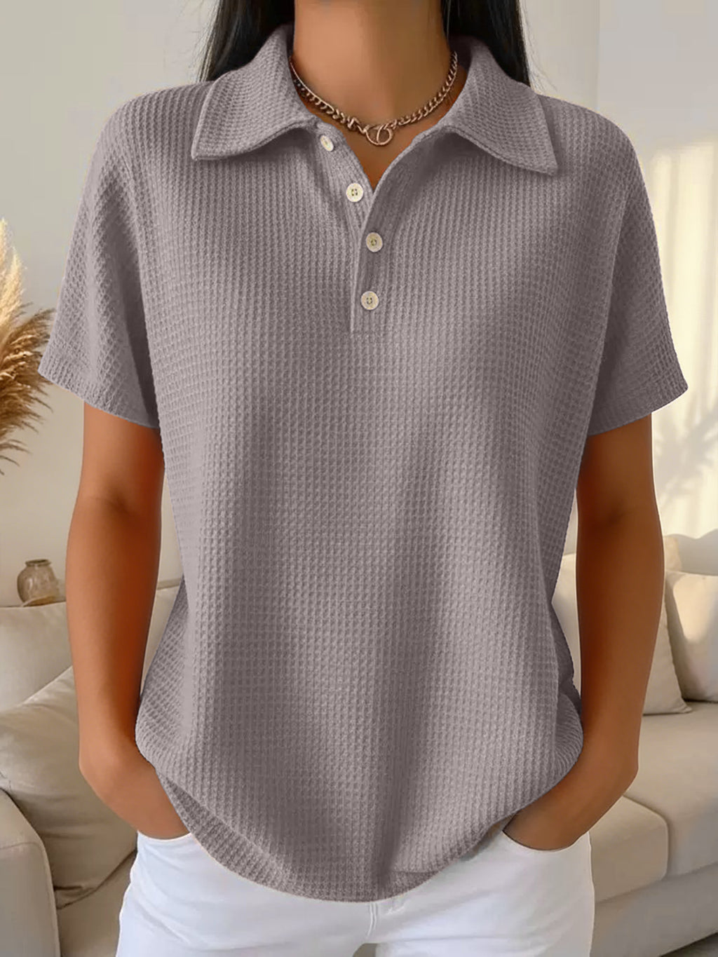 Person wearing a textured gray polo shirt in a living room setting