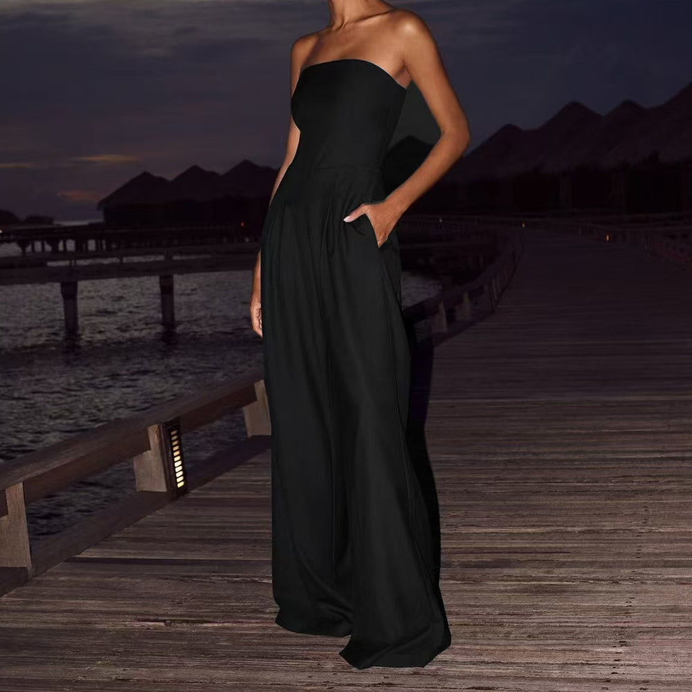Woman in a black strapless gown standing on a wooden dock at dusk.