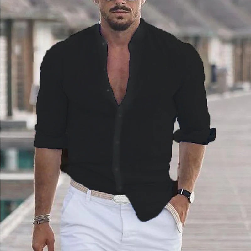 Man wearing a black open-neck shirt and white pants outdoors