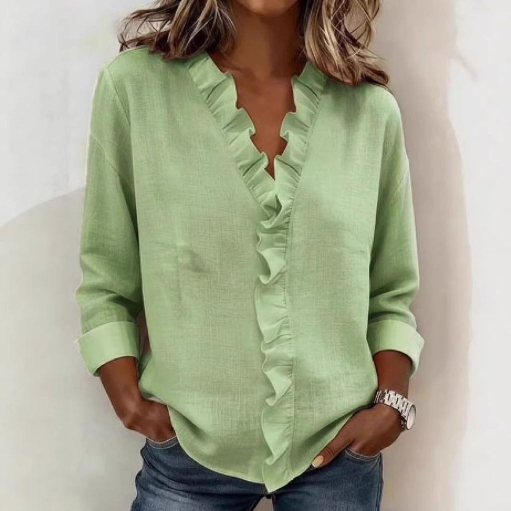 Person wearing a green blouse with ruffled details on a white background