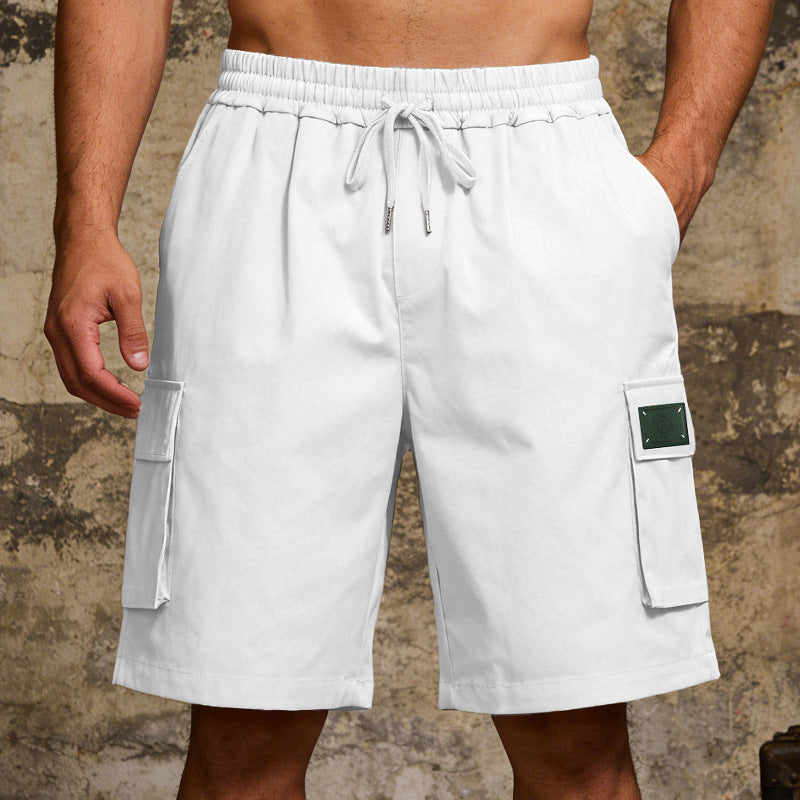 White cargo shorts worn by a person against a textured wall background