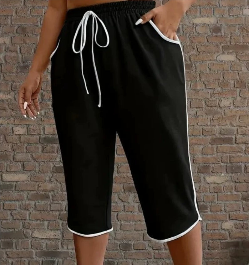 Black shorts with white trim worn by a person against a brick wall.