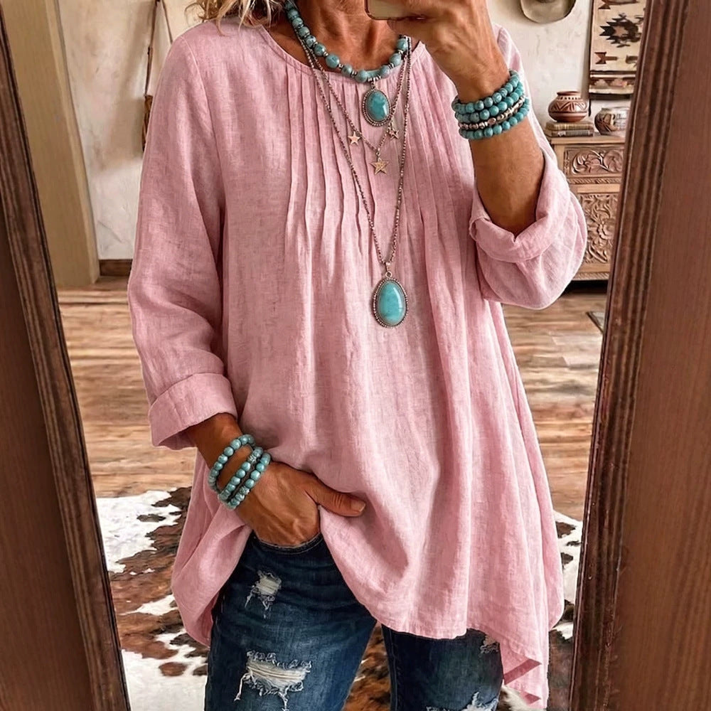 A woman takes a mirror selfie wearing a light pink linen-blend tunic top with three-quarter sleeves, paired with distressed blue jeans and layered turquoise and silver jewelry.