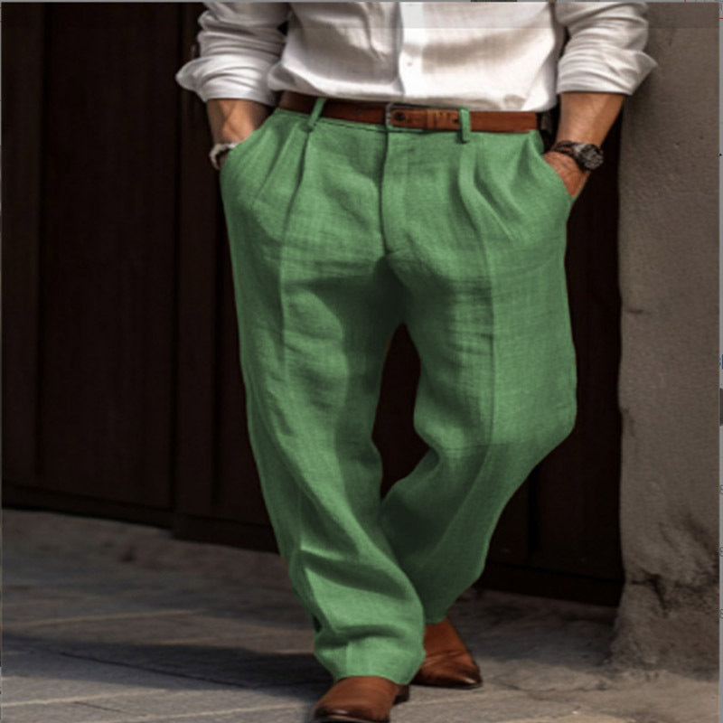 Person wearing green pleated pants and a white shirt against a dark background