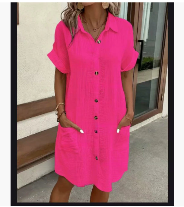 Person wearing a bright pink dress with button details outdoors.