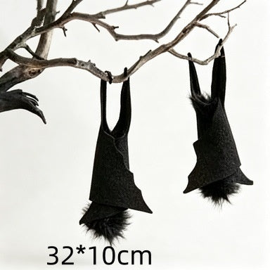Two black bat-shaped hanging decorations with fluffy faux fur, suspended from bare tree branches against a white background, with size text '32*10cm' at the bottom.