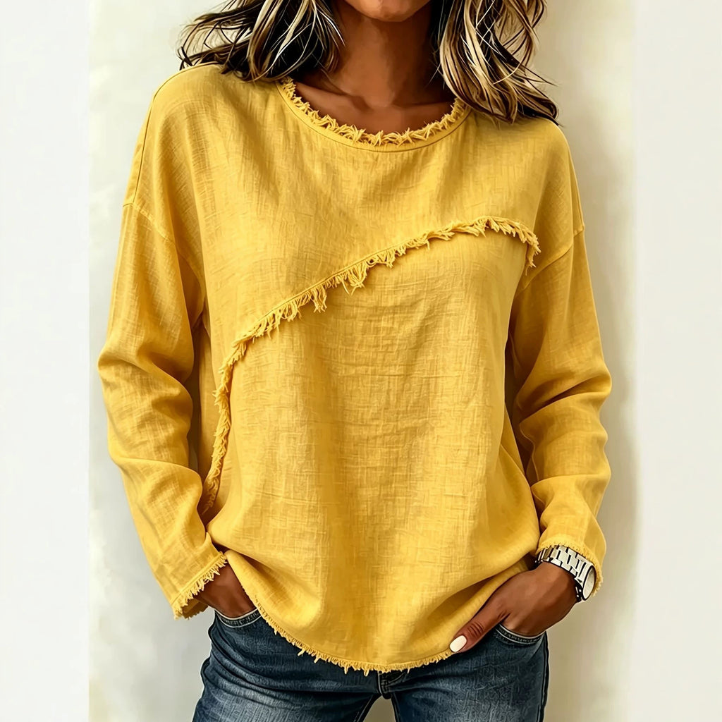 Person wearing a yellow long-sleeve top with frayed edges on a plain background