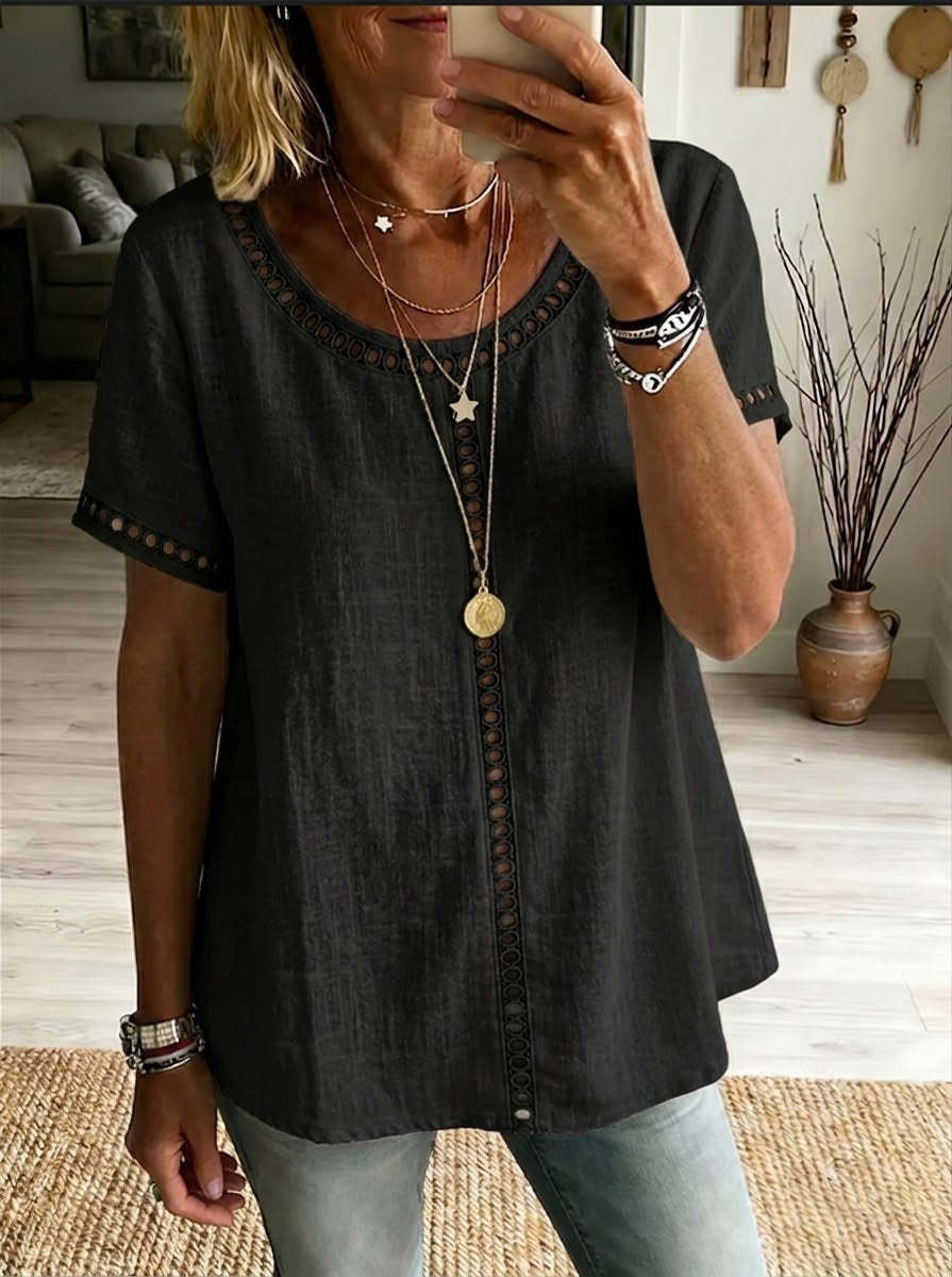Person wearing a black top with decorative buttons in a home setting