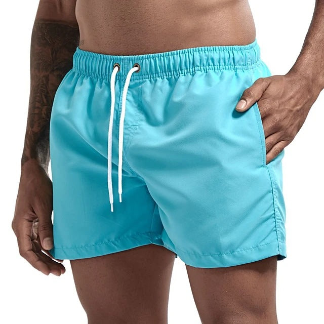 Turquoise swim shorts with a white drawstring on a neutral background