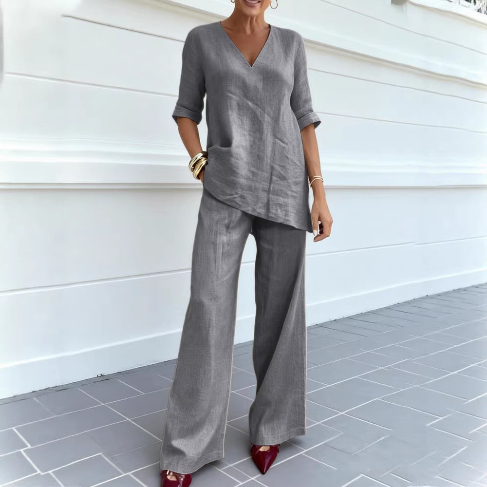 Person wearing a gray outfit standing against a white wall.
