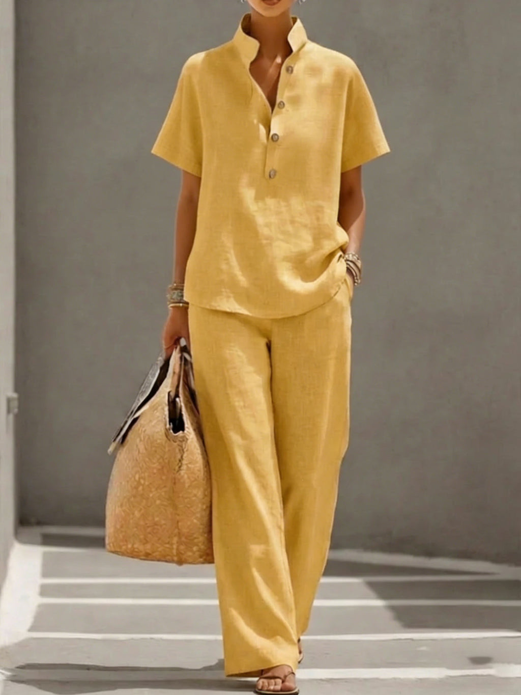 Person wearing a yellow outfit holding a woven bag on a gray background