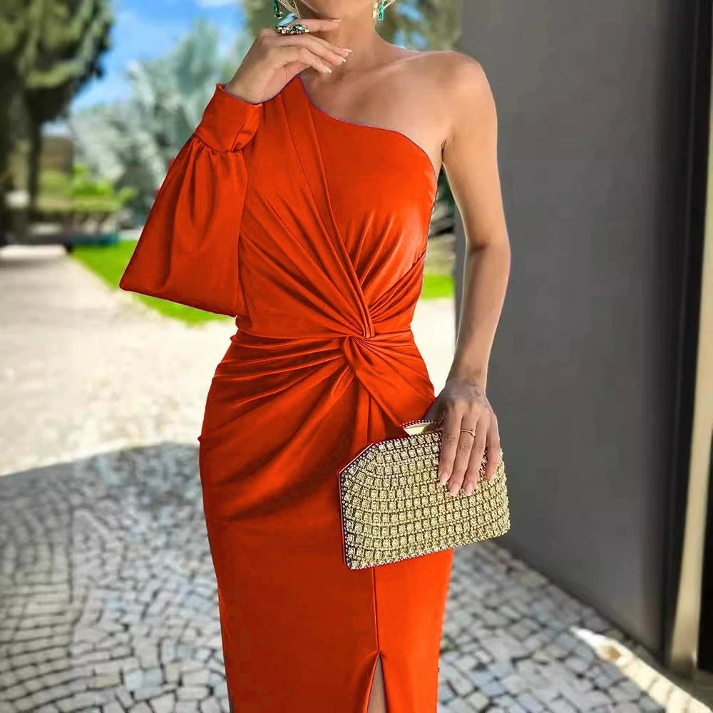 Woman in a red one-shoulder dress holding a gold clutch outdoors.