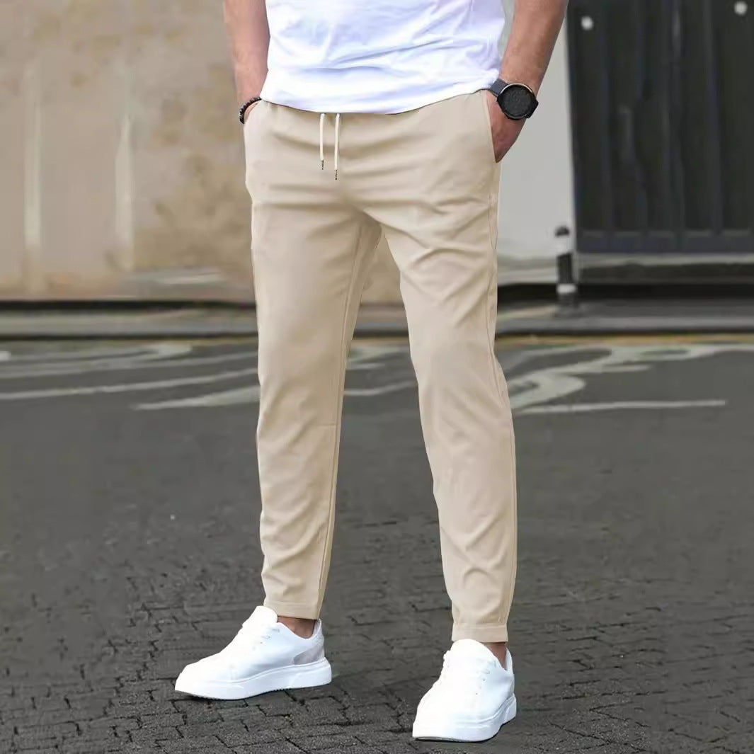 Person wearing beige pants and white sneakers on a street.