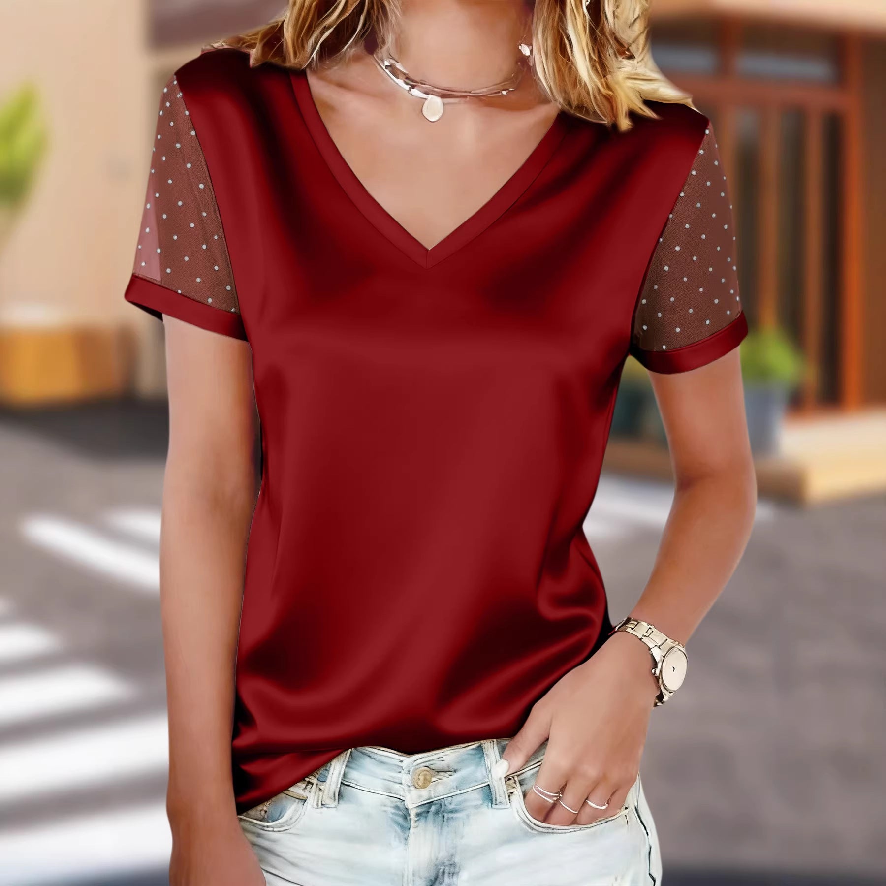 Woman wearing a red blouse with sheer sleeves in an outdoor setting
