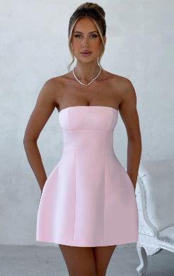 Woman wearing a pink strapless dress against a white background