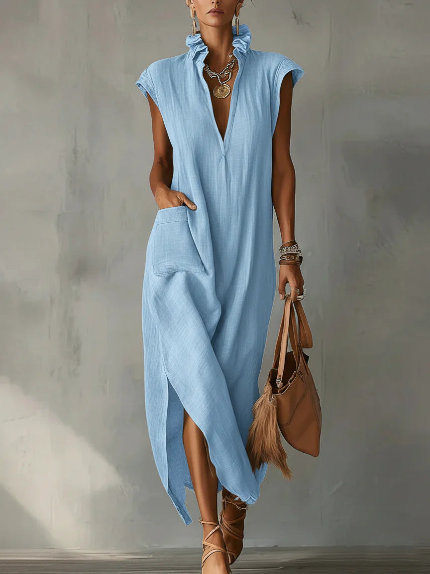 Woman wearing a light blue dress holding a brown handbag against a gray background