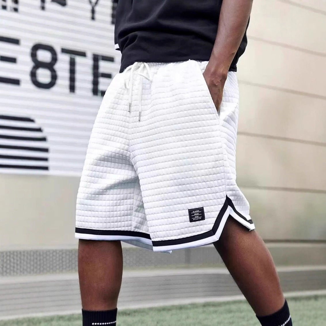 Person wearing white quilted shorts with black accents in an outdoor setting.