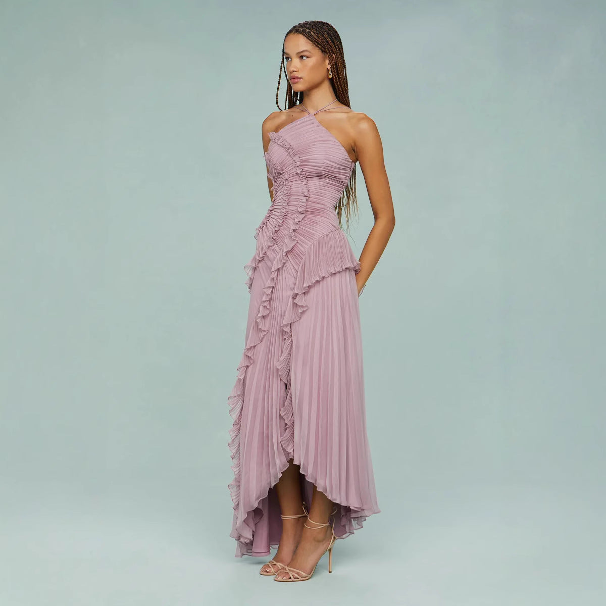 Woman wearing a pink one-shoulder dress with ruffles on a light blue background