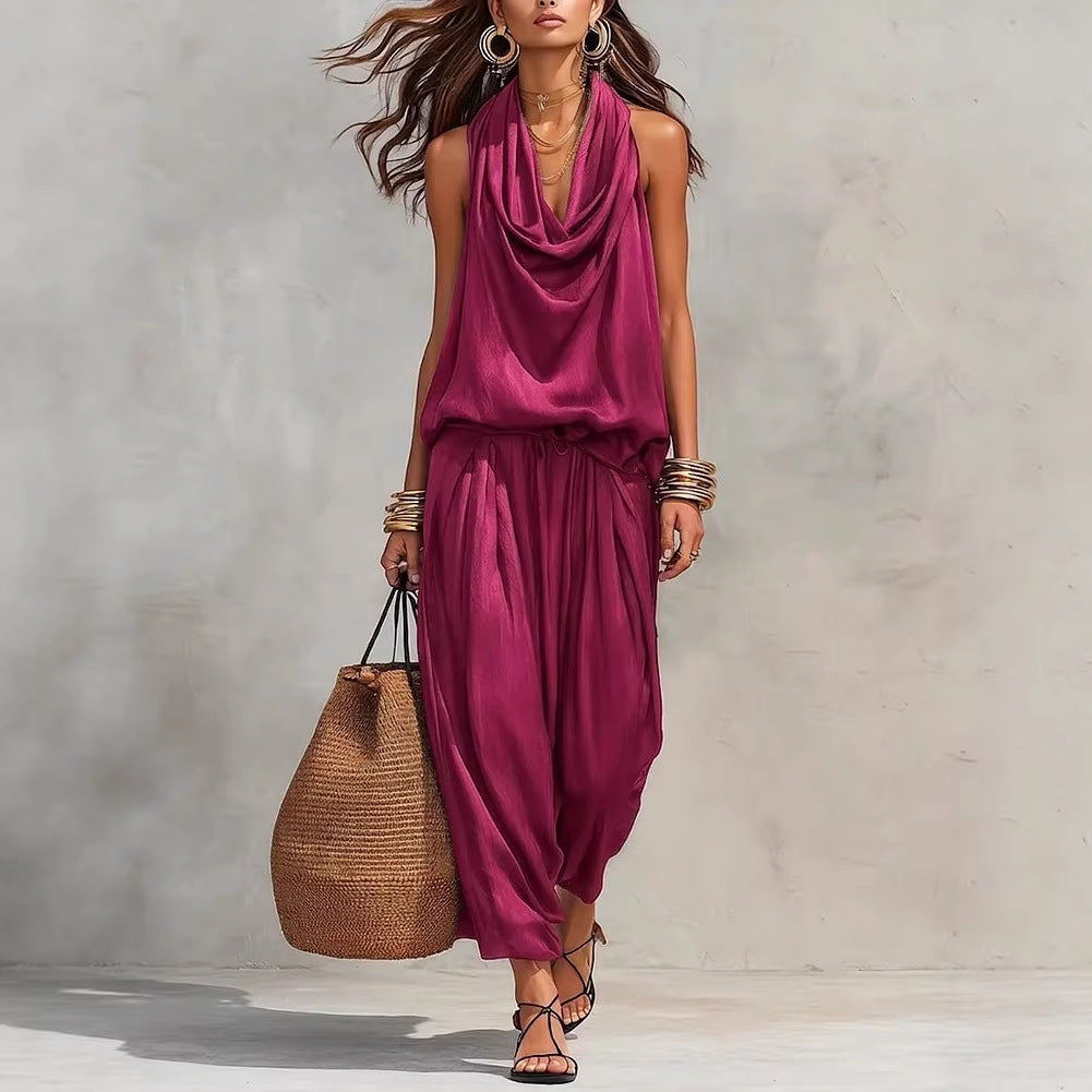 Woman wearing a magenta sleeveless top and harem pants, holding a woven bag against a neutral background.