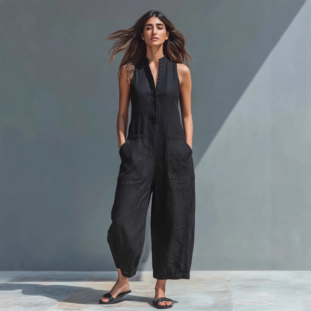 Woman wearing a black sleeveless jumpsuit against a gray background