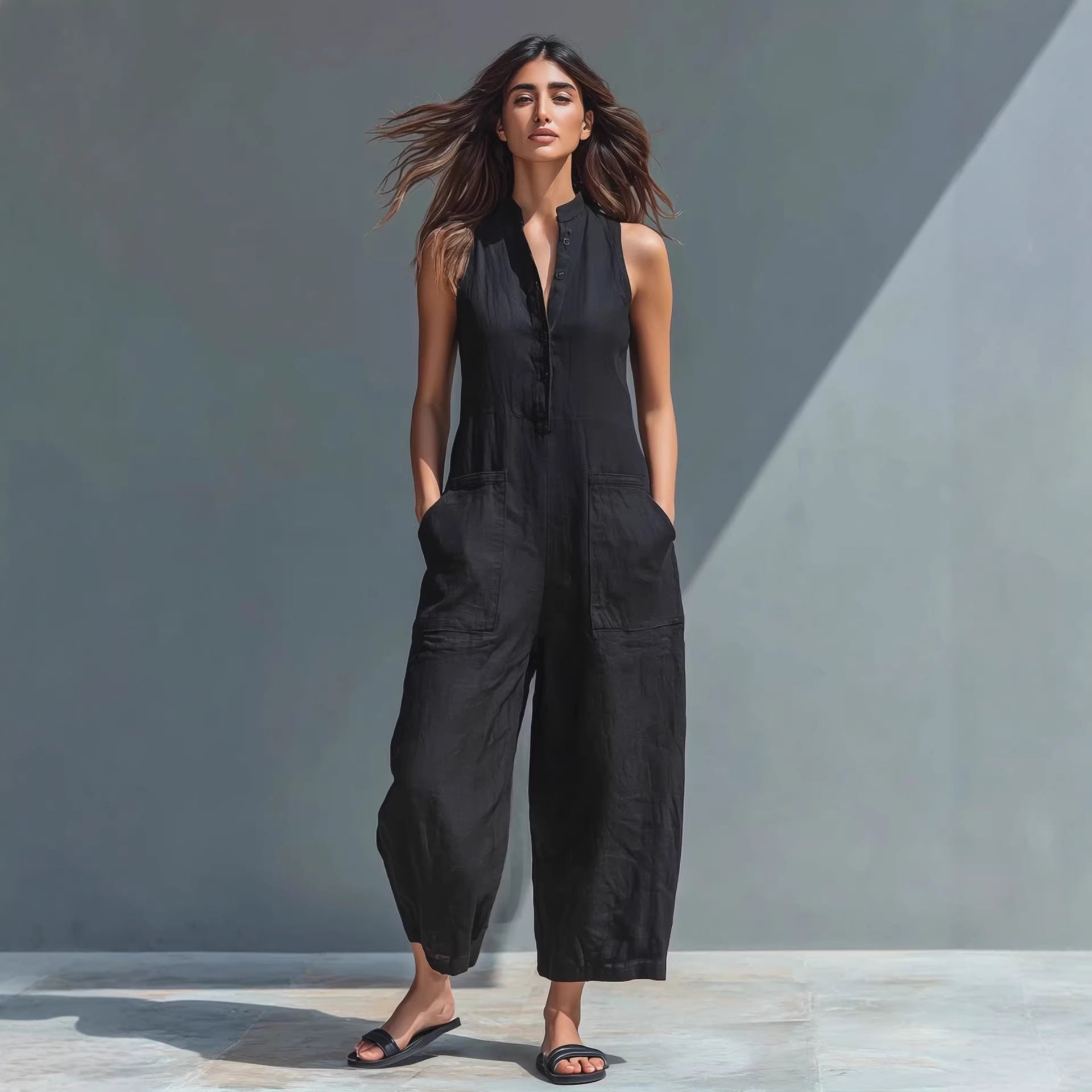 Woman wearing a black sleeveless jumpsuit against a gray background