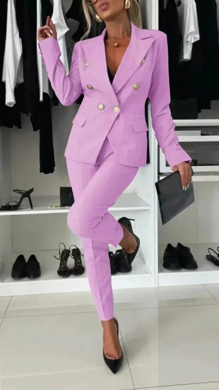 Woman in a stylish light purple blazer suit with gold buttons from ZA-Zola, holding a black clutch, standing in a chic wardrobe setting.