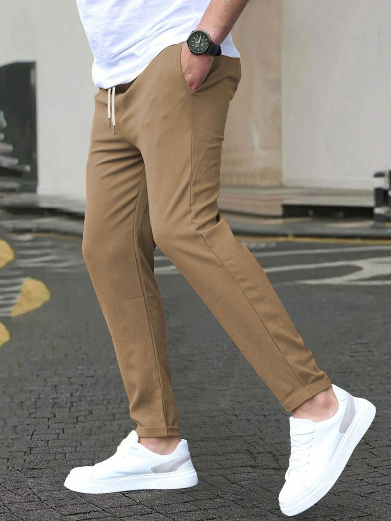Person wearing brown pants and white sneakers on a street.