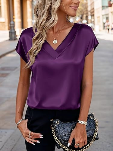 Woman wearing a purple top and black pants with a handbag on a city street.