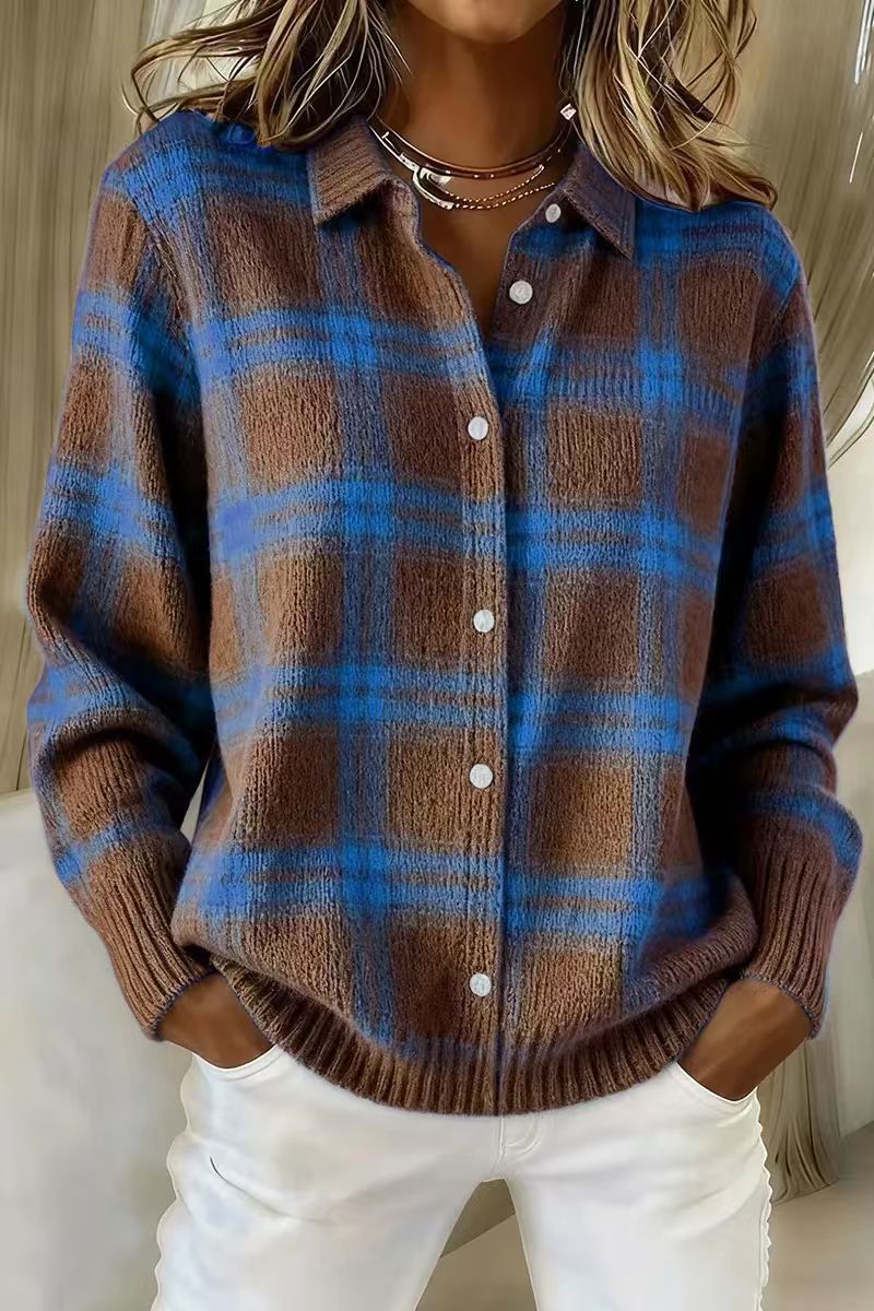 Person wearing a brown and blue plaid sweater with white pants indoors.