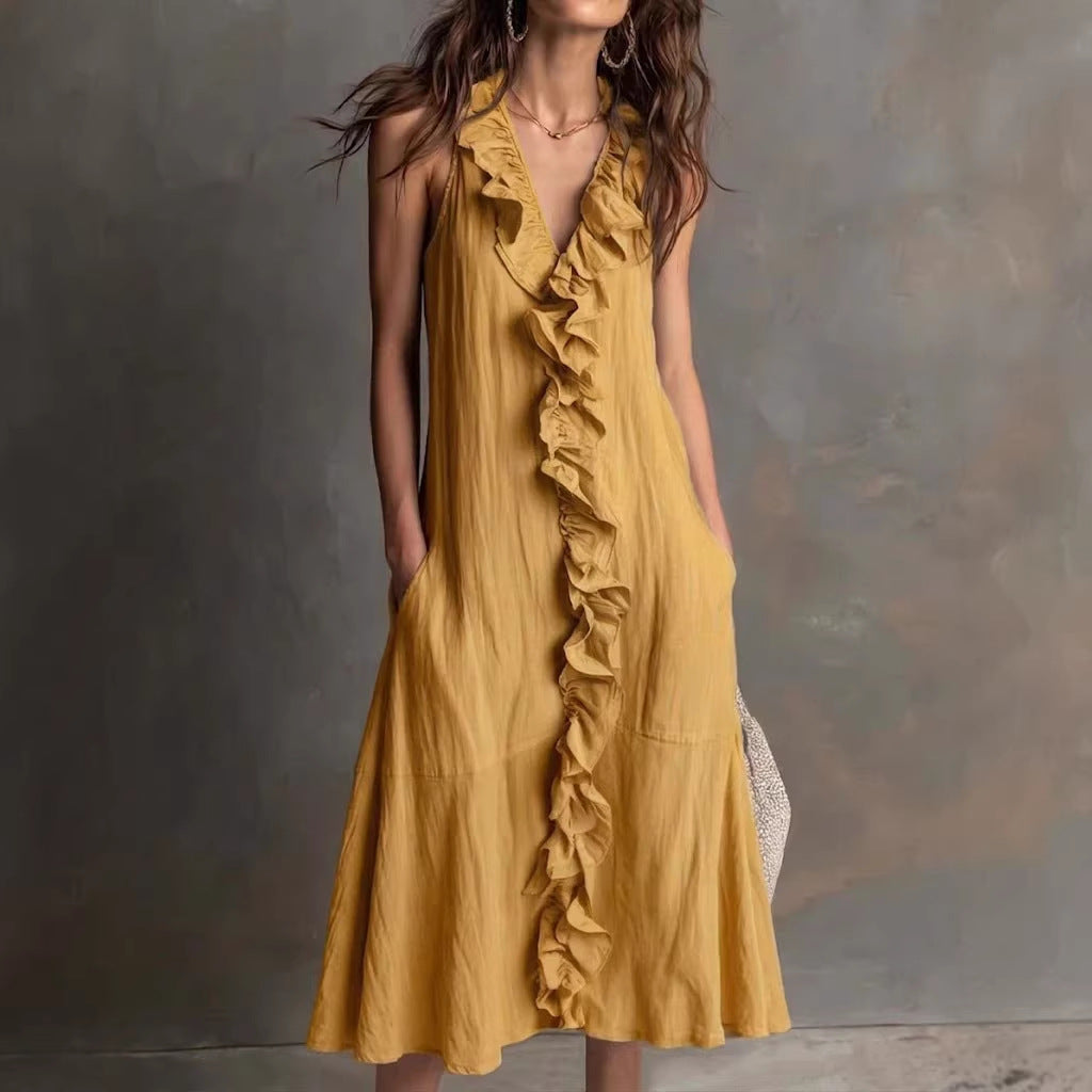 Woman wearing a mustard yellow ruffled dress against a textured gray background