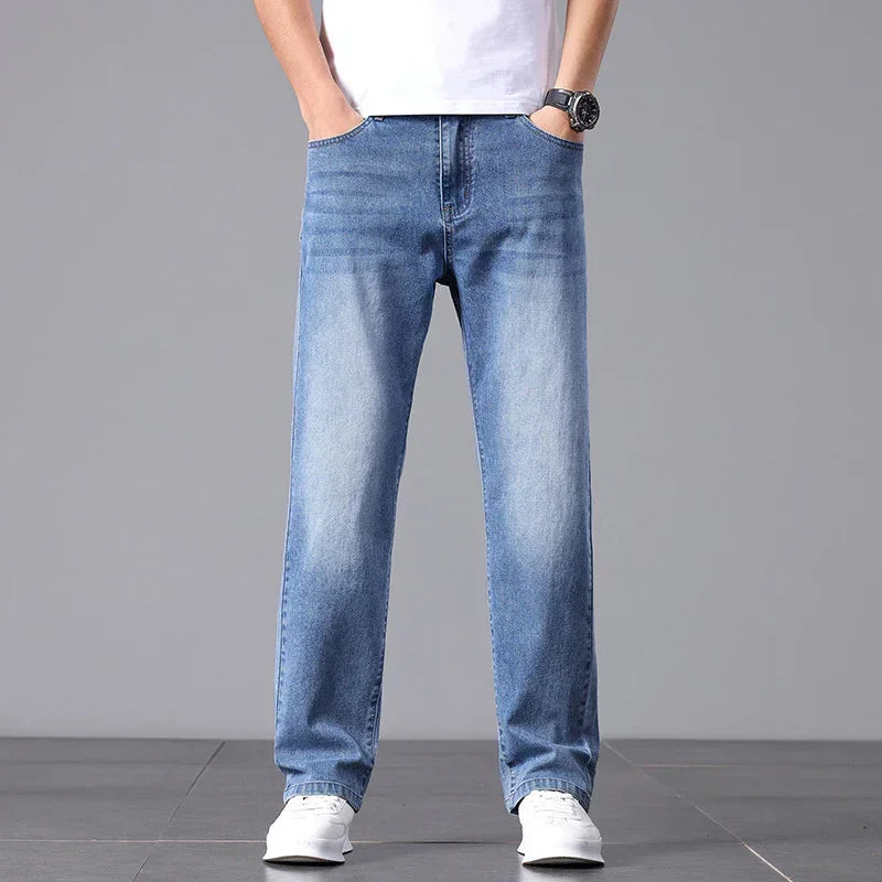 Person wearing light blue jeans and white sneakers on a gray background