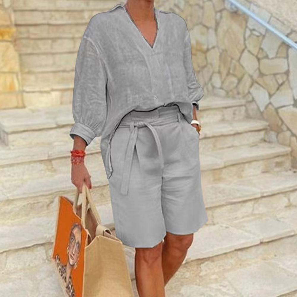 Person wearing a gray outfit with shorts and a top, standing on stone steps.