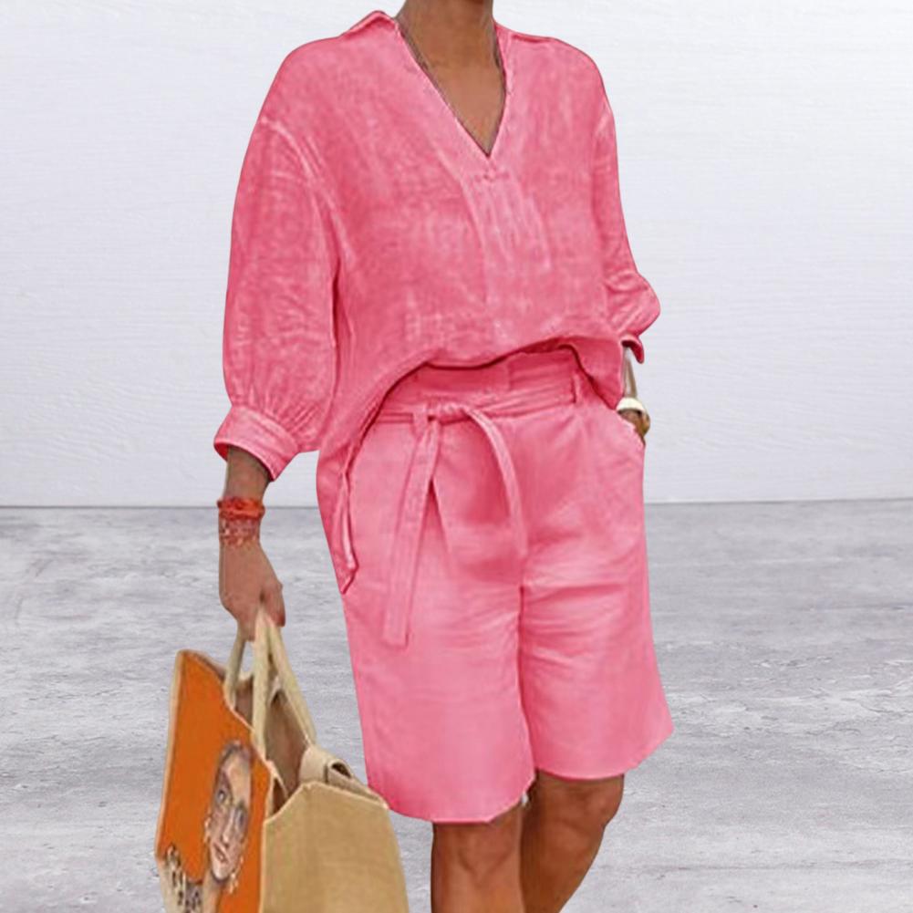 Person wearing a pink outfit holding a beige bag on a light wooden floor.