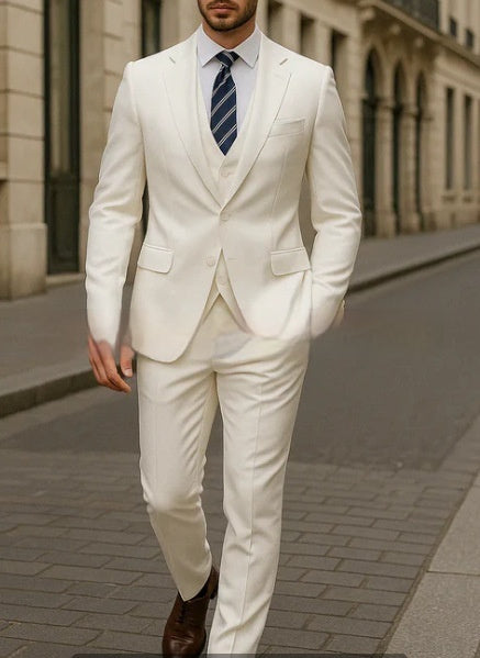 Man wearing a white suit with a blue tie walking on a city street.