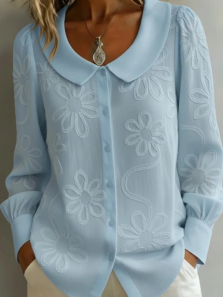 Light blue blouse with floral embroidery on a neutral background