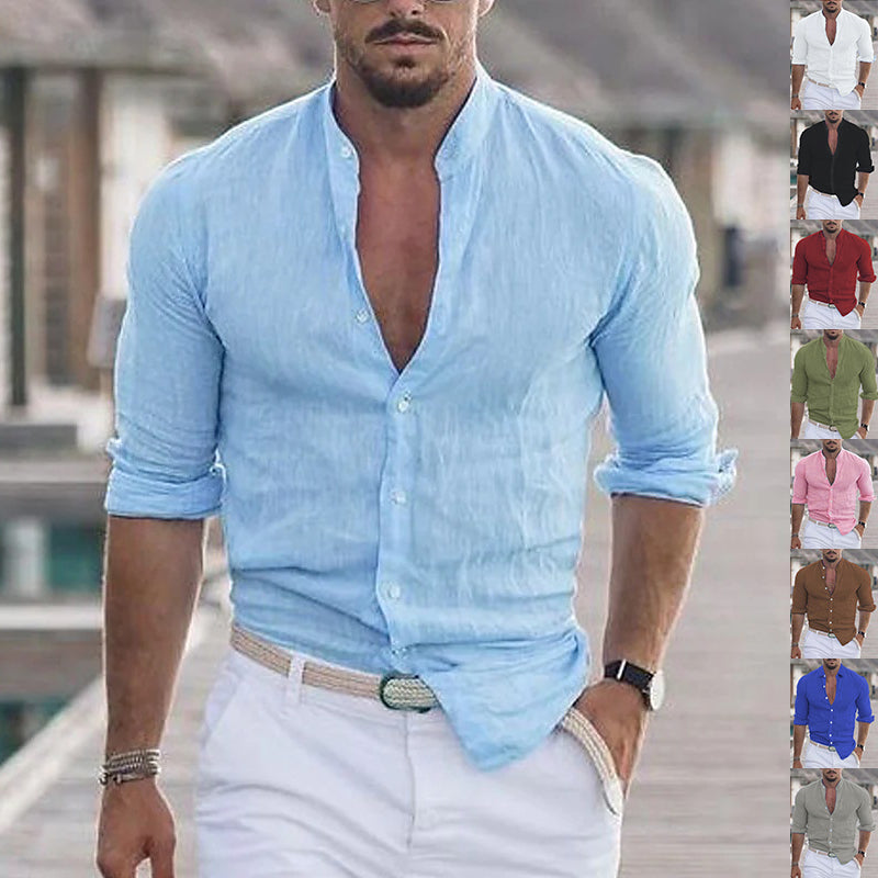 Man wearing a light blue button-up shirt with rolled-up sleeves and white pants, standing on a bridge.