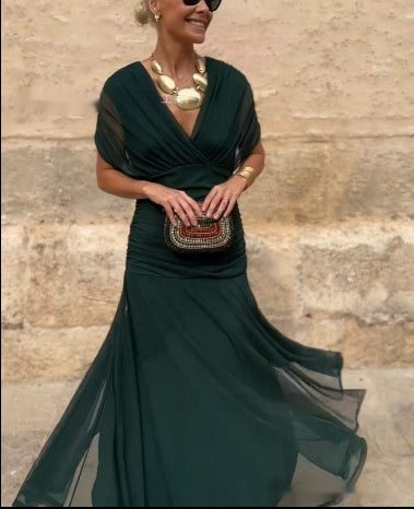 Woman in a dark green evening gown with a textured wall background
