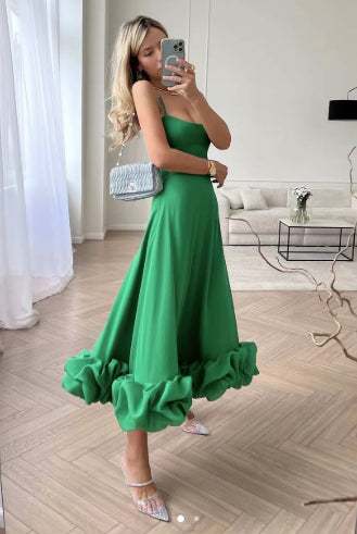 Woman in a green dress taking a mirror selfie in a modern living room.