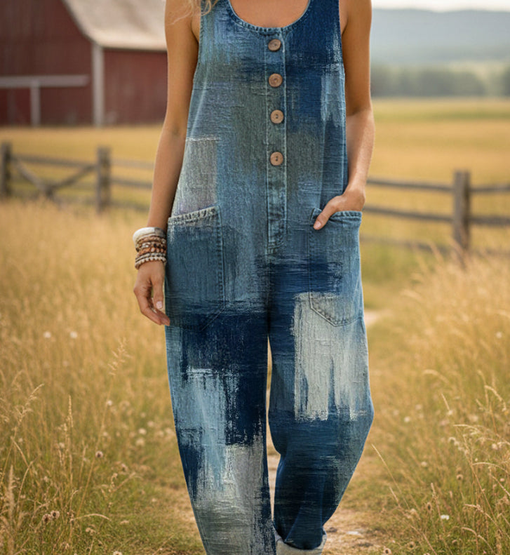 Person wearing a patchwork denim jumpsuit standing in a field with a red barn in the background.