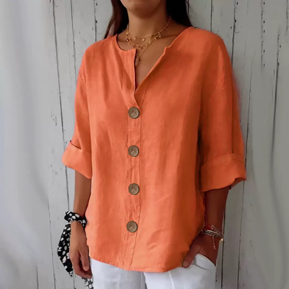 Person wearing an orange button-up shirt against a wooden background