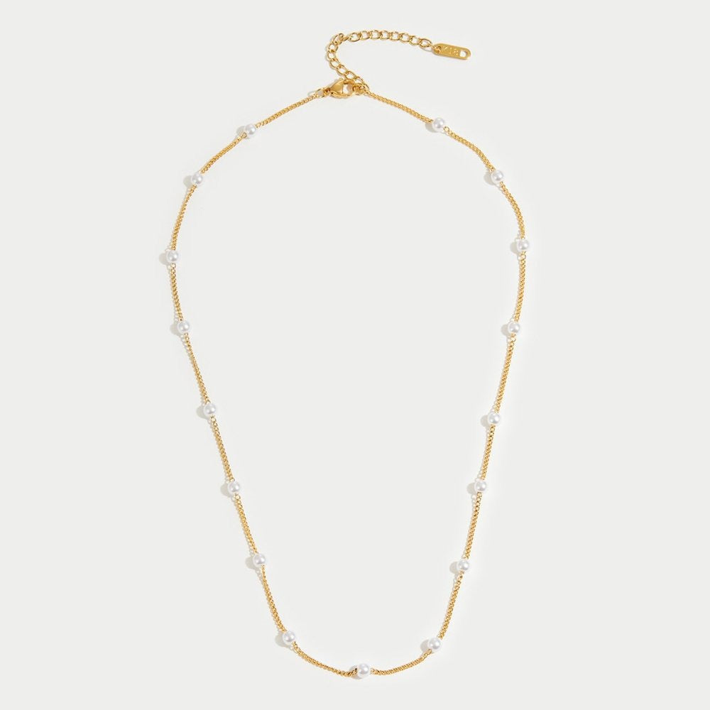 Gold necklace with pearls on a light gray background