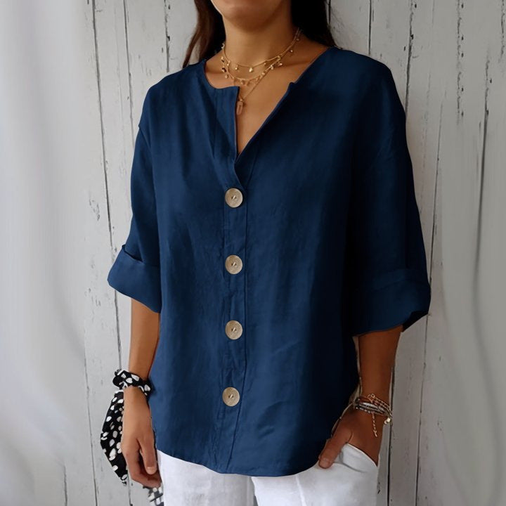 Person wearing a blue button-up shirt against a wooden background