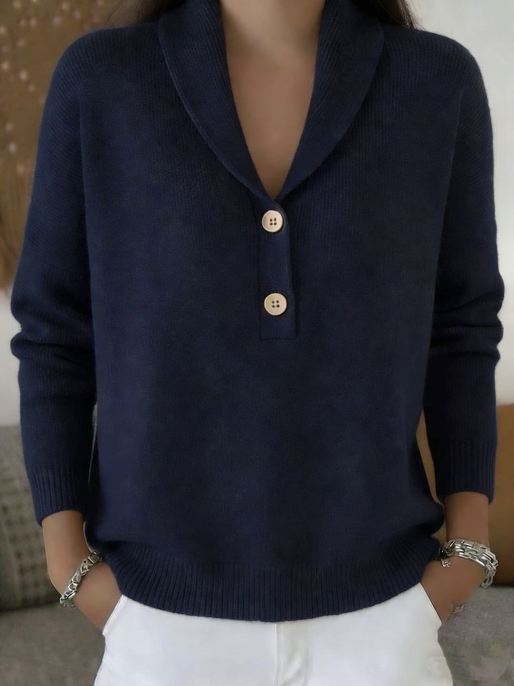 Person wearing a navy blue sweater with gold buttons against a neutral background