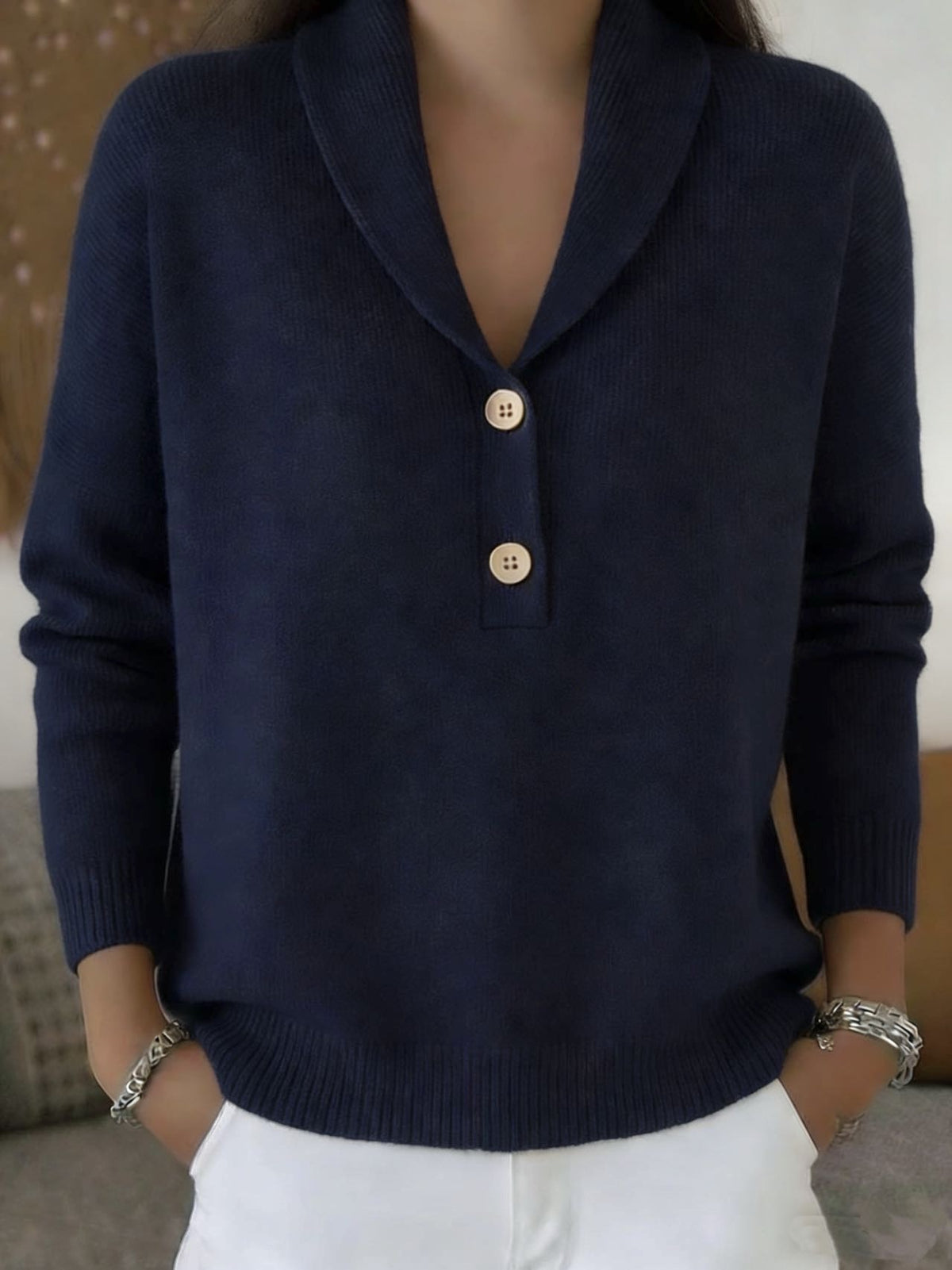 Person wearing a navy blue sweater with gold buttons against a neutral background